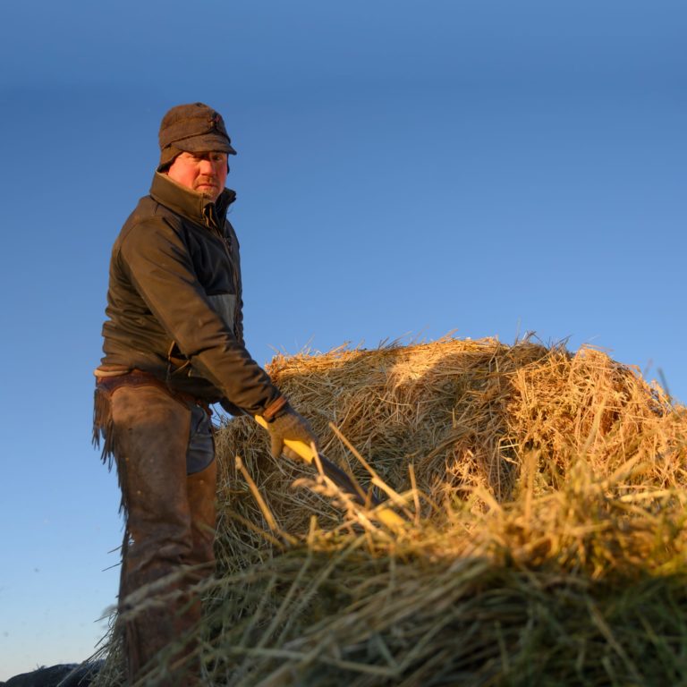 farmer moving hay bail